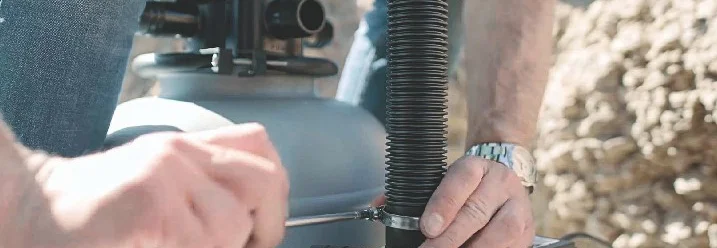 Person montiert Schlauch mit Schraubendreher.